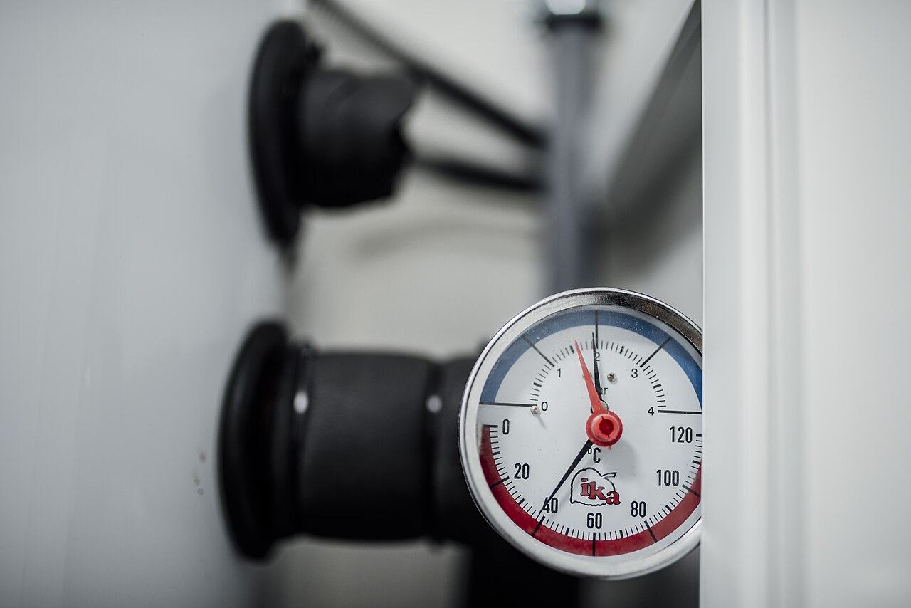 Pressure gauge on workshop equipment surrounded by tools and machinery